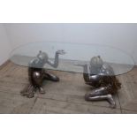 Blackamoor coffee table, the oval glass top on two silvered kneeling male figures (37cm x 58cm x