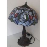Tiffany style table lamp with cast metal bronzed base in the form of lilies and lead glazed shade (