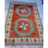 Turkish rug with two octagonal medallions on a red ground in repeating floral border (216cm x 124cm)