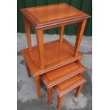A nest of three cherry wood finish tables and matching side table
