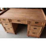 Late Victorian striped pine knee-hole desk with central drawer flanked by six short drawers, with