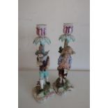 Pair of 20th C continental figural candlesticks, of figures standing before tree stumps,