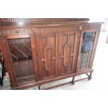 20th C Jacobean style oak low bookcase with central panelled doors flanked by glazed cupboards, on