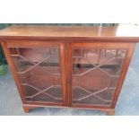 Mahogany three tier bookcase enclosed by glassed doors (cracked), on raised bracket supports (