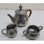 Tudric hammered pewter bachelors three piece tea service, the tea pot with wicker bound handle and