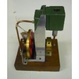 Small model of a stationary engine, with red and brass fly wheel on wooden base