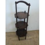 20th C oak cake stand, the three octagonal tiers on square supports with gilt dot work decoration