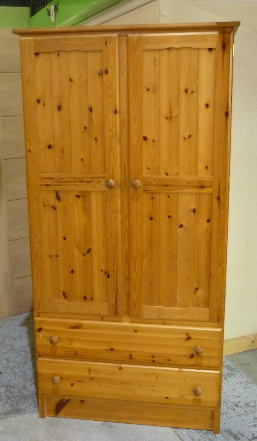 Polished pine wardrobe enclosed by two panelled doors, with two drawers to the base (186cm x 94.