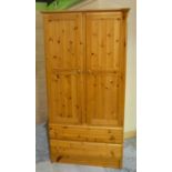 Polished pine wardrobe enclosed by two panelled doors, with two drawers to the base (186cm x 94.