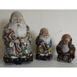 Set of three Japanese polychrome decorated models of immortals, each with white beard, on carved