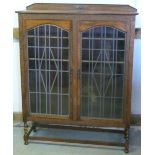 1930s oak display cabinet, with raised back and a pair of arch glazed doors on barley twist supports