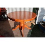 Light wood circular extending dining table on single column with four outsplayed supports (