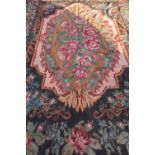 20th C tapestry rug, black ground central medallion with pink roses and rose patterned border (237cm