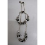 Pandora necklace, the black and white floral cylindrical charms stamped 925, and a similar