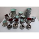Studio pottery: collection of mugs, jugs, flower vases etc decorated with foliage, fish, etc on grey