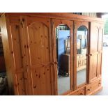 Extremely large modern pine wardrobe comprising of two central mirrored panelled doors flanked by