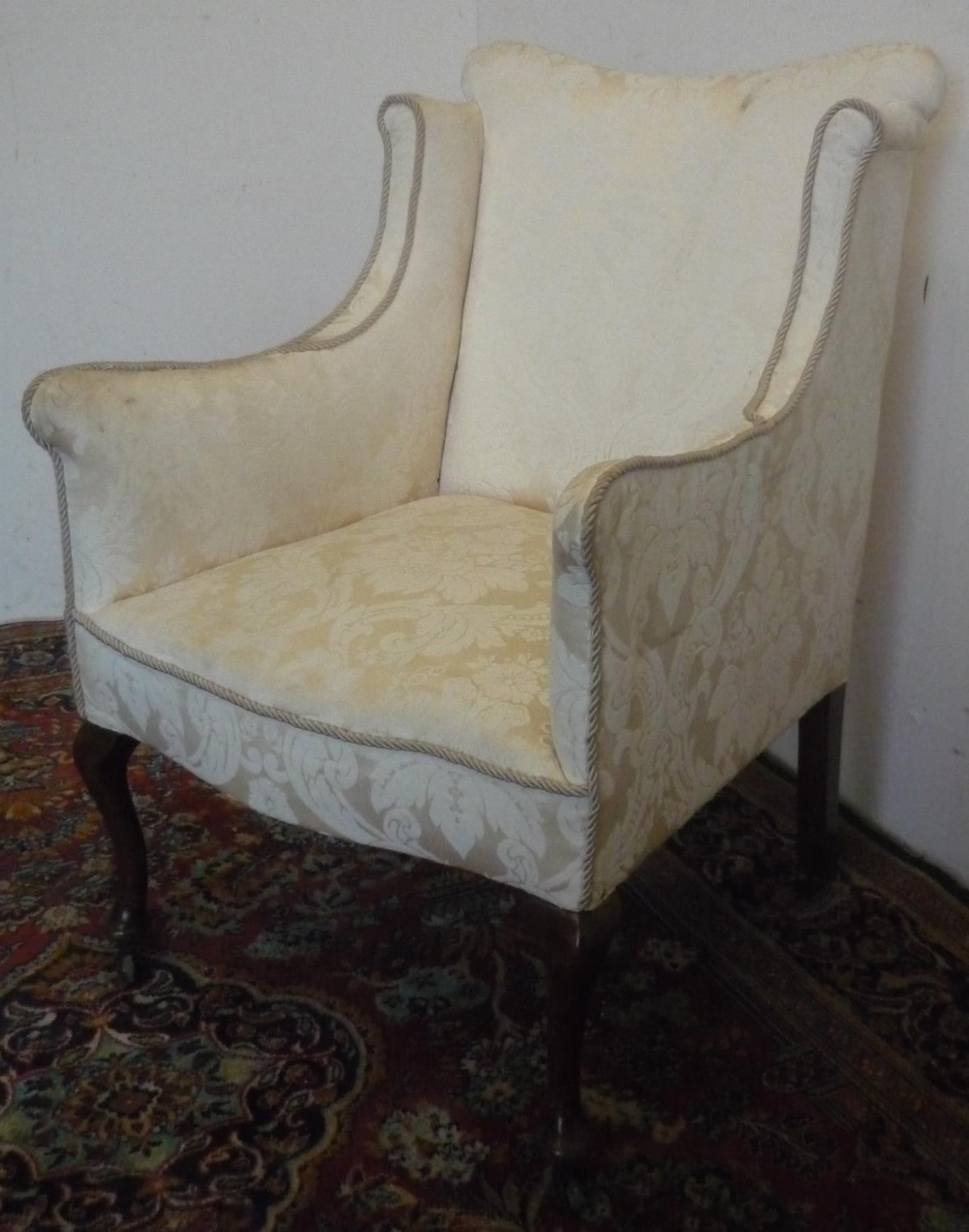 Small Edwardian upholstered armchair, shaped wing back and serpentine seat on slender cabriole