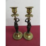 Pair of bronze and gilt metal table candlesticks in the form of semi-clad females holding urns