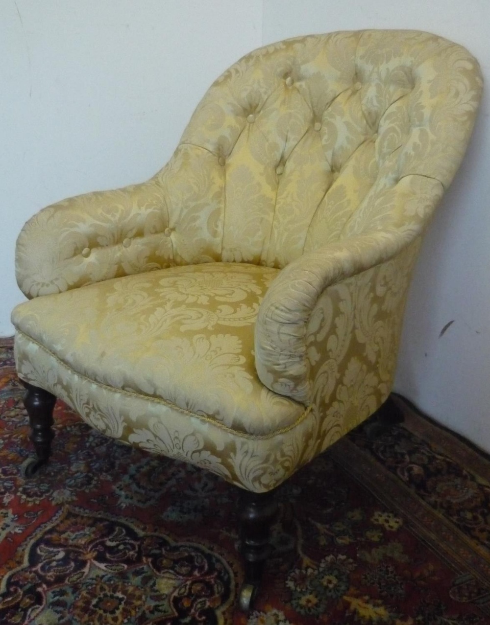 Victorian upholstered armchair, with deep buttoned curved back and downswept arms on turned supports