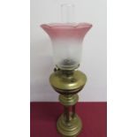 Early 20th C brass oil lamp with etched rose tinted shade on 3 column supports and turned circular
