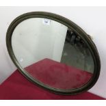 Oval wall mirror in moulded antique gilt and green frame, retailers label on reverse, John Magee