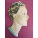 Art Deco relief bust of a lady with curled hair and red lipstick and a green Art Deco style wall