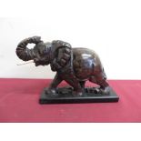 Polished hardstone model of an elephant with bone tusks on a wooden plinth (H20cm)