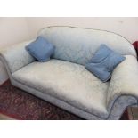 Edwardian upholstered drop-end sofa with arched back on turned wooden, with two plain scatter