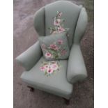 Large Geo.III style wingback armchair, upholstered in green with needlework floral detail, on shell