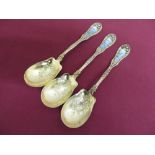 Set of three 19th C continental silver gilt spoons, the floral handles enamelled with garden