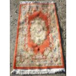 20th C Chinese embossed washed woollen rug, rust ground with central floral pattern medallion,