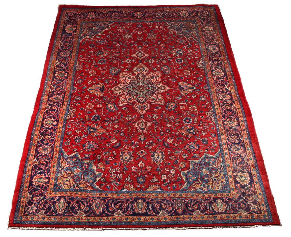 A Hamadan woollen hand-made carpet with red ground, 120 by 89ins. (305 by 225cms.).