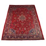 A Hamadan woollen hand-made carpet with red ground, 120 by 89ins. (305 by 225cms.).