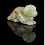 A Chinese carved pale celadon & russet jade model of a recumbent lion cub, 2.35ins. (6cms.) long.