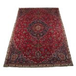 A Meshed woollen hand-made carpet with red ground, 124 by 81ins. (315 by 206cms.).