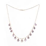 An unmarked yellow gold amethyst fringe necklace, with thirteen hexagonal cut amethysts, with sprung