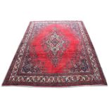 A Hamadan woollen hand-made carpet with red ground, 163 by 125ins. (412 by 317cms.).