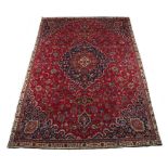 A Meshed woollen hand-made carpet with red ground, 124 by 81ins. (315 by 206cms.).