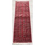 Property of a deceased estate - a Turkoman design long rug with two rows of guls on a burgundy
