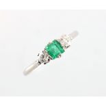 A platinum emerald & diamond three stone ring, the vibrant green rectangular cut emerald weighing an