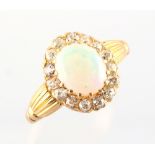 A yellow gold opal & diamond cluster ring, with reeded shoulders, the oval opal measuring