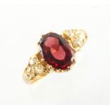 A yellow gold almandine garnet & diamond ring, the oval cut almandine garnet weighing