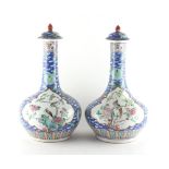 A pair of Chinese blue ground famille rose bottle vases & covers, late 19th / early 20th century,