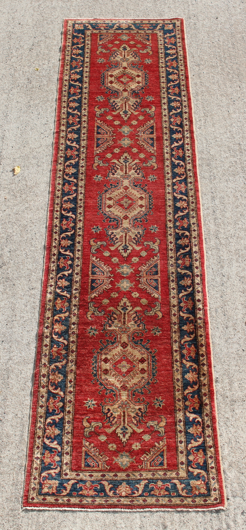 Property of a deceased estate - a Kazak style hand knotted runner, with red ground, 132 by 33ins. (