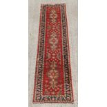 Property of a deceased estate - a Kazak style hand knotted runner, with red ground, 132 by 33ins. (