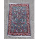 A Kerman woollen hand-made rug with blue ground, 59 by 37ins. (150 by 94cms.).