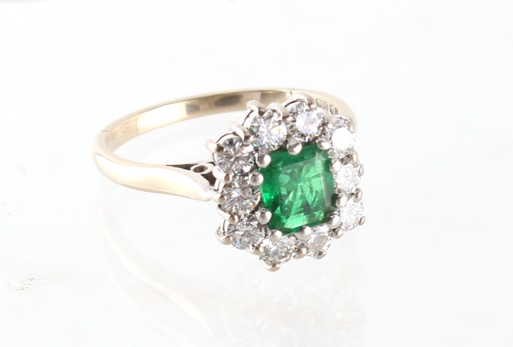 Property of a lady - an 18ct white gold emerald & diamond cluster ring, the emerald cut emerald