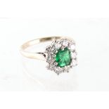 Property of a lady - an 18ct white gold emerald & diamond cluster ring, the emerald cut emerald