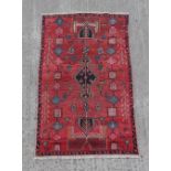 A Hamadan woollen hand-made rug with red ground, 69 by 42ins. (175 by 117cms.).