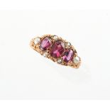 A late 19th / early 20th century 15ct yellow gold garnet & seed pearl ring, with three oval